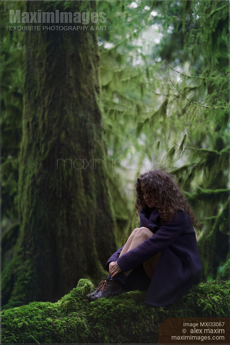 Woman with thoughtful contemplative expression sitting on mossy tree trunk in deep green forest with hands around her legs Stock photo of Woman with thoughtful contemplative expression sitting on mossy tree trunk in deep green forest with hands around her legs Buy commercial use license at MaximImages