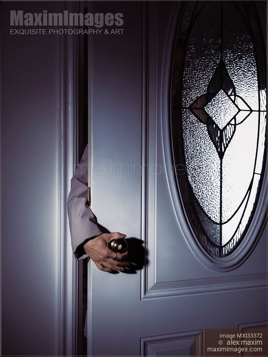 Woman's hand reaching for a door handle from behind a dark shadowy house front door Stock photo of Woman's hand reaching for a door handle from behind a dark shadowy house front door Buy commercial use license at MaximImages