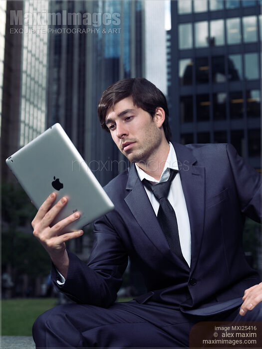 Stock photo of Young businessman with Apple iPad in a city Buy commercial use license at MaximImages