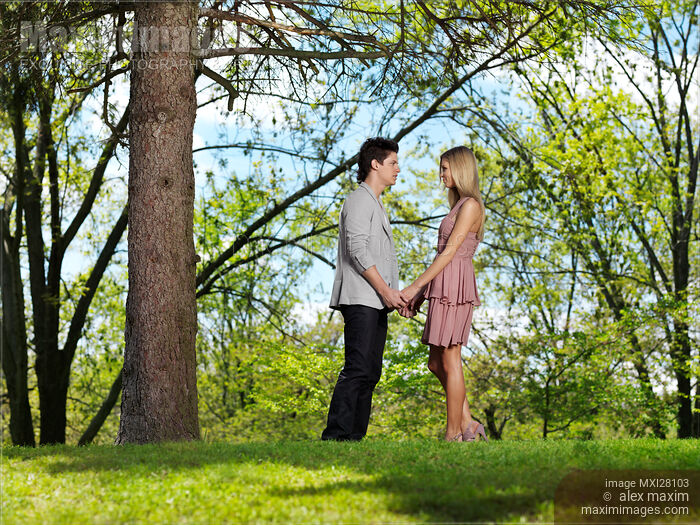 Young couple holding hands in a park Stock photo of Young couple holding hands in a park Buy commercial use license at MaximImages