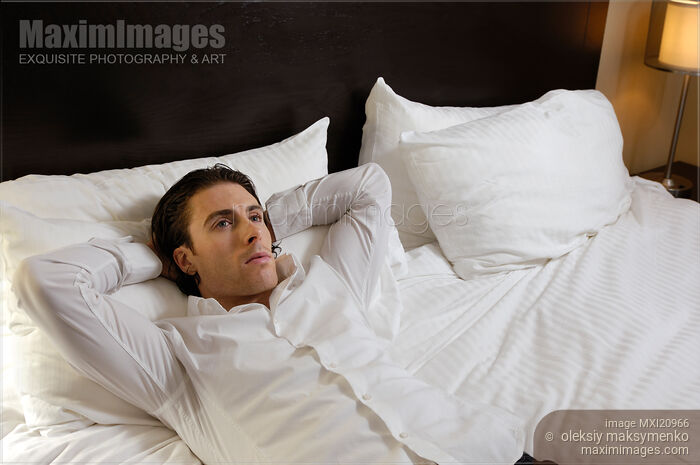 Stock photo of Young Man Lying Alone in Bed Buy commercial use license at MaximImages