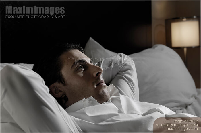 Stock photo of Young Man Lying in Bed Alone Buy commercial use license at MaximImages