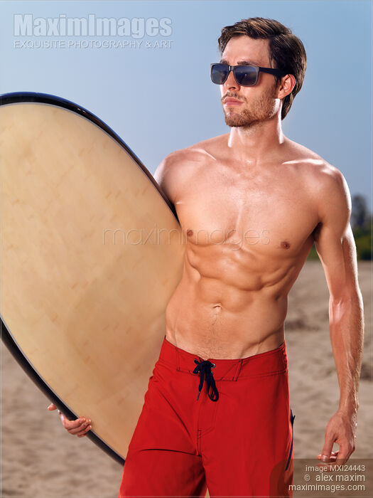 Stock photo of Young man with a surfboard at the beach Buy commercial use license at MaximImages