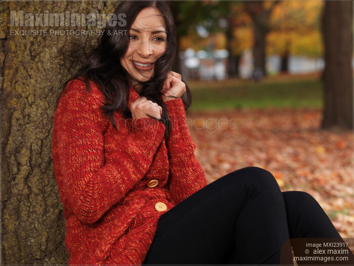 Young Smiling Woman Cuddling in a Sweater in the Wind Stock photo of Young Smiling Woman Cuddling in a Sweater in the Wind Buy commercial use license at MaximImages