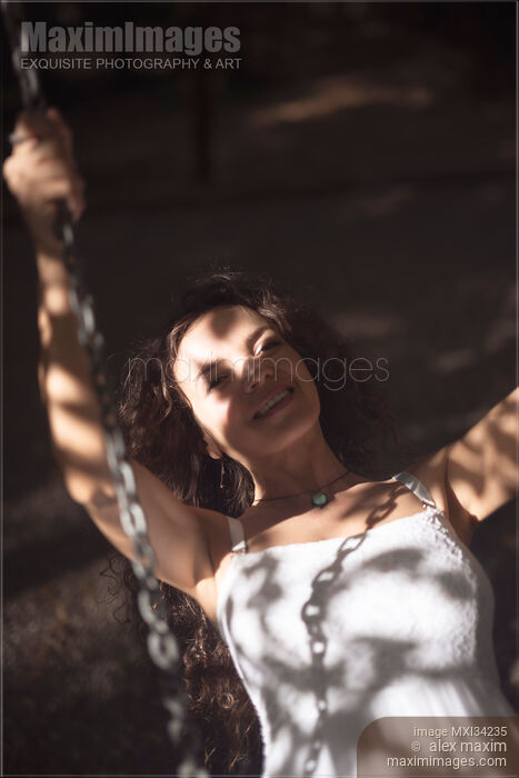 Stock photo of Young smiling woman riding on a swing Buy commercial use license at MaximImages