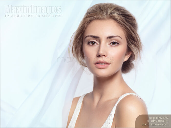 Young woman beautiful face portrait on light blue background Stock photo of Young woman beautiful face portrait on light blue background Buy commercial use license at MaximImages