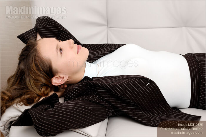 Stock photo of Young Woman in Business Suit Relaxing on Sofa Buy commercial use license at MaximImages