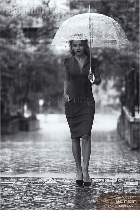 Young woman in elegant dress with umbrella walking thoughtfully in the rain Black and white Stock photo of Young woman in elegant dress with umbrella walking thoughtfully in the rain Black and white Buy commercial use license at MaximImages