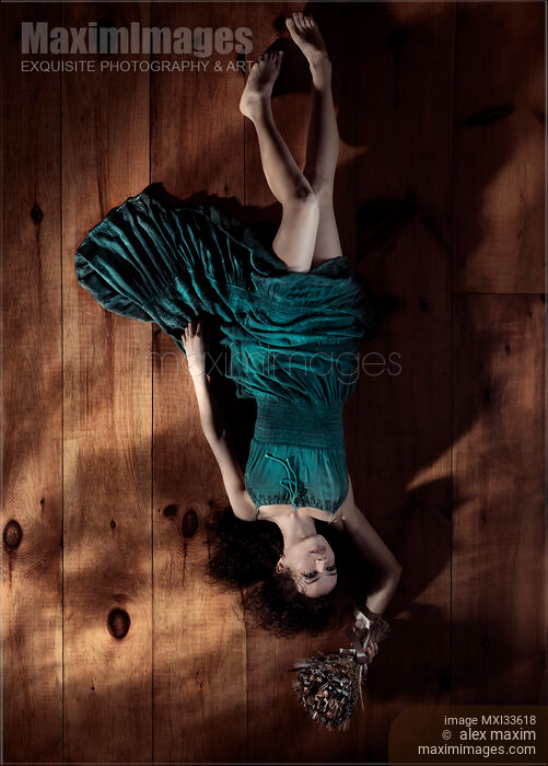 Young woman in green dress lying on the floor upside down with flowers Stock photo of Young woman in green dress lying on the floor upside down with flowers Buy commercial use license at MaximImages