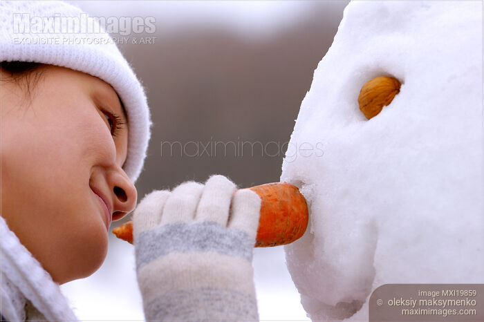 Stock photo of Young Woman Making Snowman Buy commercial use license at MaximImages