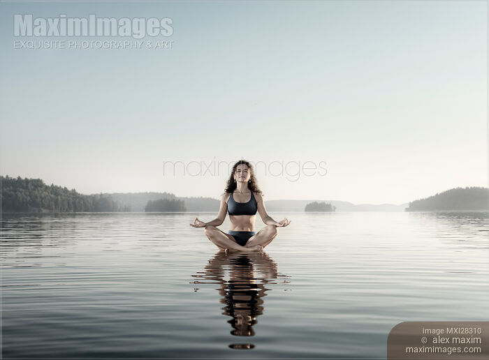 Young woman meditating on platform in the water Stock photo of Young woman meditating on platform in the water Buy commercial use license at MaximImages