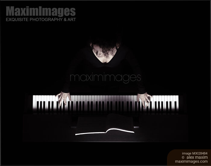 Stock photo of Young woman playing piano artistic overhead view on black Buy commercial use license at MaximImages