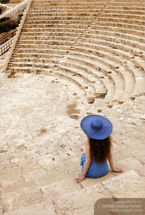 Stock photo of Young woman sitting alone on steps of historic amphitheatre Buy commercial use license at MaximImages