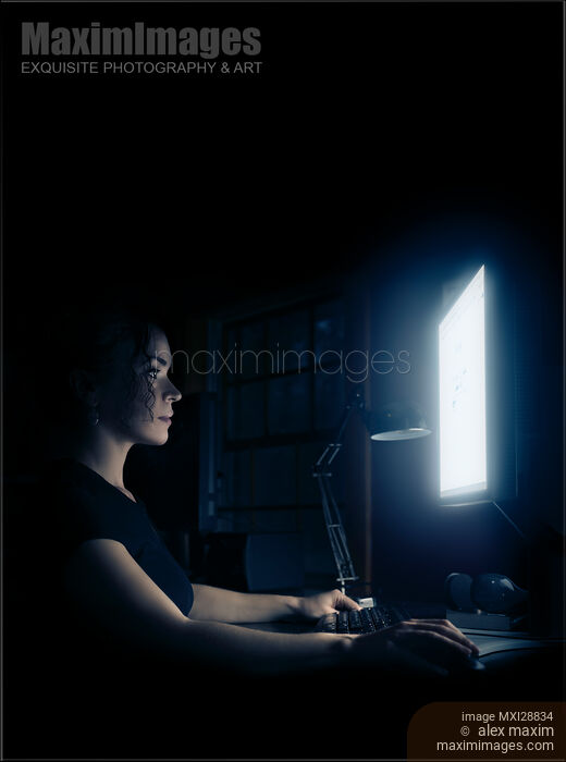 Stock photo of Young woman sitting at night in front of a computer display Buy commercial use license at MaximImages