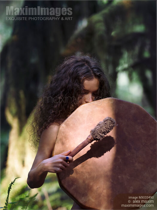 Stock photo of Young woman with a shamanic drum in a tranquil forest scenery Buy commercial use license at MaximImages