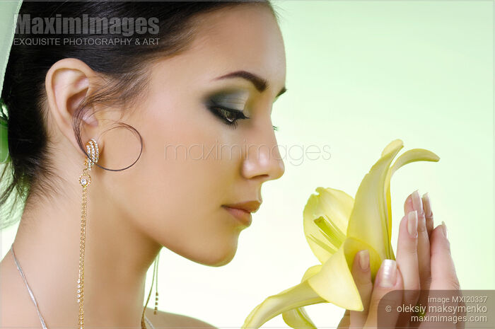 Stock photo of Young Woman with a Yellow Lily Buy commercial use license at MaximImages