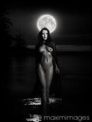 Beautiful mysterious woman in white face mask with sensual nude body walking out of the water like a goddess in full moon. Black and white
