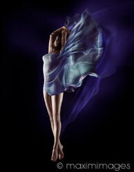 Beautiful nude woman floating in mid-air with flowing blue cloth wrapped around her body