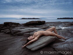 Limited edition print: Beautiful nude young woman lying naked stretched on ocean shore rock in graceful relaxed pose in nature scenery MaximImages.com