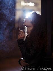 Beautiful woman smoking a cigarette standing on a night city street