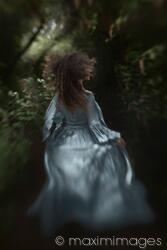 Dramatic rear view portrait of a woman running away into a deep dark forest